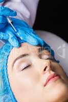 Woman receiving botox injection on her forehead