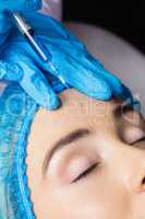 Woman receiving botox injection on her forehead