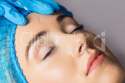 Woman receiving botox injection on her forehead