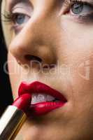 Woman putting lipstick on her lips