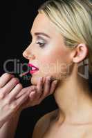 Blonde woman having her lips made up by makeup artist