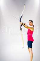 Composite image of sportswoman practicing archery on a white bac