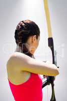 Composite image of rear view of sportswoman doing archery on a w
