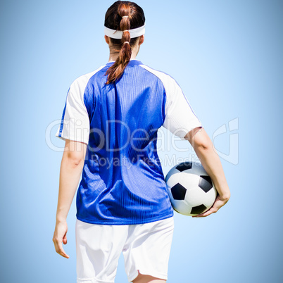 Composite image of rear view of woman soccer player holding a ba