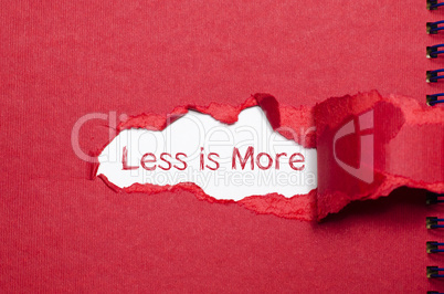 The word less is more appearing behind torn paper.