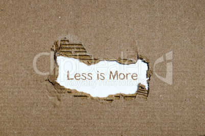 The word less is more appearing behind torn paper.