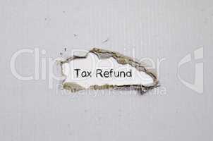 The word tax refund appearing behind torn paper.