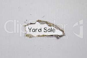 The word yard sale appearing behind torn paper.