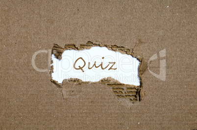 The word quiz appearing behind torn paper.