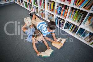School kids lying on floor and reading a book in library