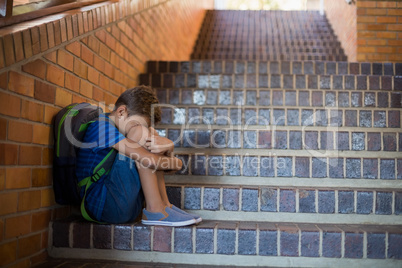 Sad schoolboy sitting alone on staircase