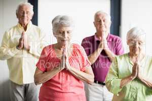 Seniors doing yoga with closed eyes