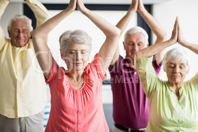 Seniors doing yoga with closed eyes