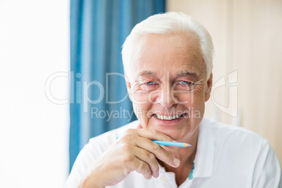 Smiling senior holding coloured pencil