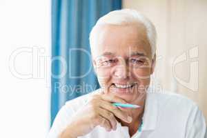 Smiling senior holding coloured pencil