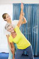 Instructor helping senior woman with sport exercises