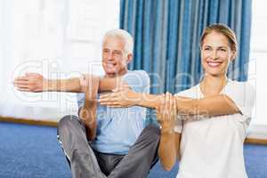 Instructor helping senior man with sport exercises