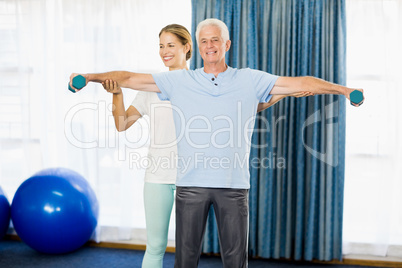 Instructor helping senior man with weights