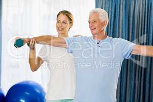 Instructor helping senior man with weights
