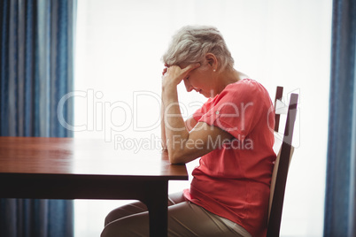 Sad senior woman sitting at a table