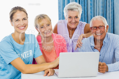 Volunteer and seniors using a laptop