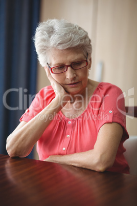 Sad senior woman sitting at a table