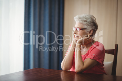 Thoughtful senior woman sitting at a table