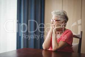 Thoughtful senior woman sitting at a table