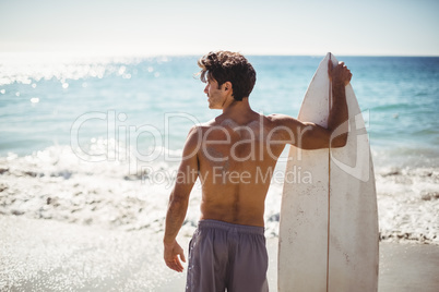 Man holding surfboard on beach