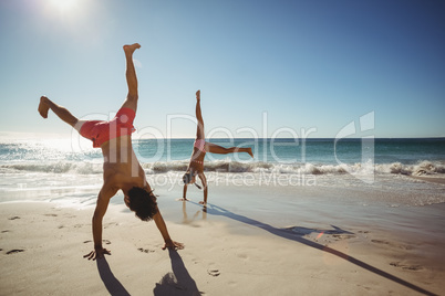 Couple performing somersault on beach