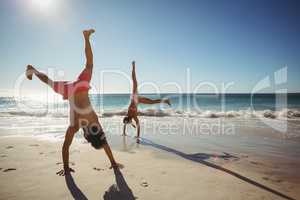 Couple performing somersault on beach