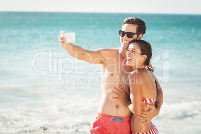 Young couple taking selfie on beach