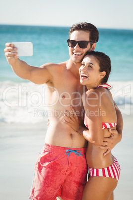 Young couple taking selfie on beach