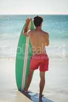 Man standing with surfboard on beach