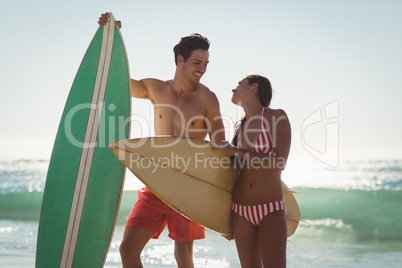 Couple standing with surfboard on beach