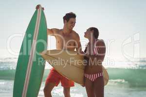 Couple standing with surfboard on beach