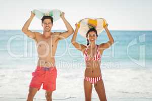 Couple posing with surfboard on beach