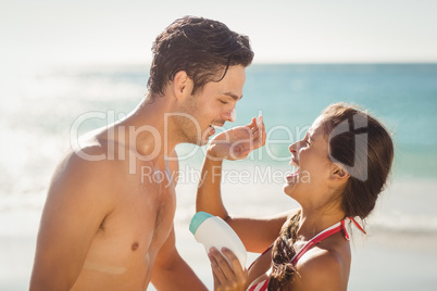 Woman applying sunscreen lotion on mans face