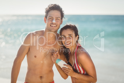Young couple with sunscreen lotion on beach