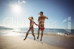 Couple wearing diving mask jumping on beach