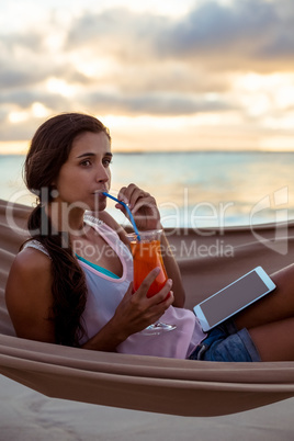 Woman having mocktail while relaxing on a hammock