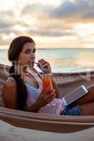 Woman having mocktail while relaxing on a hammock