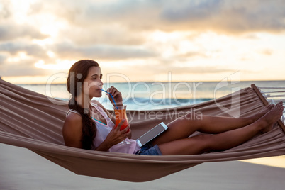 Woman having mocktail while relaxing on a hammock