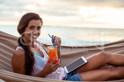 Portrait of woman holding mocktail while relaxing on a hammock