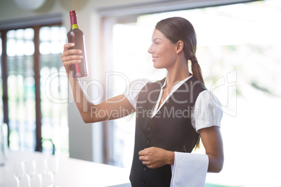 Waitress checking a wine bottle