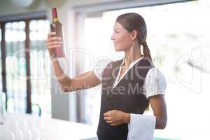 Waitress checking a wine bottle