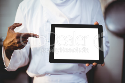 Mid section of chef holding a digital tablet
