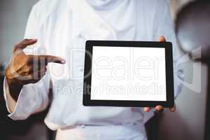 Mid section of chef holding a digital tablet