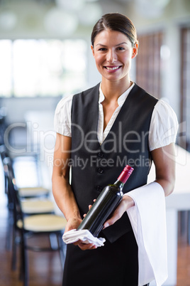 Waitress holding a bottle of red wine and a towel