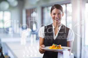 Waitress holding plate of meal in a restaurant